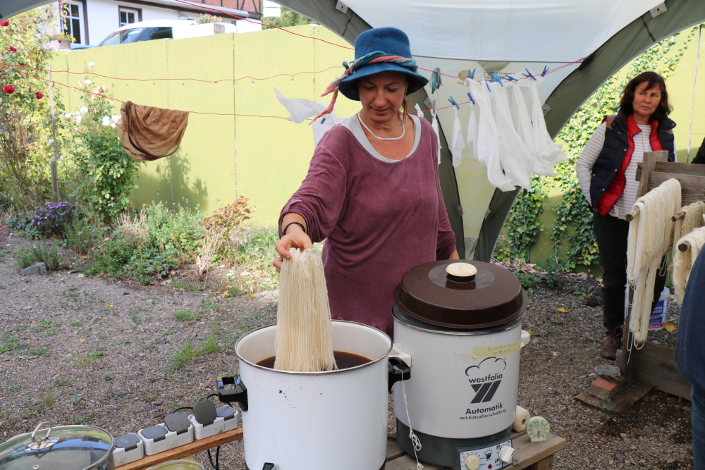 weisse Wolle wird in die Färbebrühe getaucht